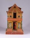 A lithographed paper-on-wood dollhouse by Whitney Reed, having a shingle and brick facade, with simulated gutters on each side