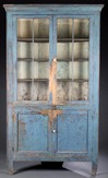 A corner cupboard with old blue paint