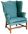 A Federal or Hepplewhite wing chair having a serpentine crest and shaped wings on mahogany straight legs joined by an H-stretcher