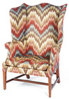 A Hepplewhite or Federal wing chair having a serpentine back crest and shaped wings on mahogany square tapered legs joined by an H-stretcher