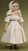 An Izannah Walker oil-painted pressed stockinette doll having hand-painted features including brown eyes, brown painted hair with center part and two spiral tendrils in front of each applied ear, pink cheek blush, and a painted closed mouth