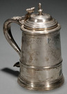 A circa 1760 silver tankard by Nathaniel Hurd (1729-1777), Boston, with an urn and flame finial on a stepped domed lid over a tapered cylindrical body with applied band at lower body