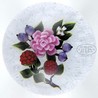 Trabucco fruit and flower bouquet paperweight. Bouquet consists of two red raspberries, 4 blueberries, pink rose and 4 white miniature blossoms with green leaves and stems. The entire design rests on a white lace ground and is signed in script