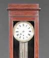 An antique French regulator mahogany tall case clock with pinwheel movement, lyre form pendulum and porcelain dial with Roman numerals within a molded brass bezel
