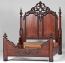 A circa 1860 rosewood Victorian Rococo Revival king size bed having a paneled headboard with elaborate pierce carved floral and bird crest between columns with turned finials, and shaped footboard with applied c-scroll decoration between two corner posts, with conforming siderails