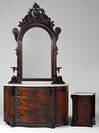 A circa 1860 two piece bedroom suite comprising a rosewood dresser and commode stand having an arched mirror with carved crest and side candle shelves over serpentine chest with white marble top and three drawers, and a white marble topped serpentine commode stand