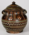An extremely rare and important lidded redware sugar jar with profuse three color slip decoration, floral, geometric and line designs, sunflowers