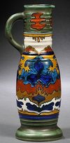 A Zuid Holland Gouda Pottery matte glaze ewer, early 20th century, with narrow ribbed neck, slender body, single handle, and flaring foot, decorated with an abstract design